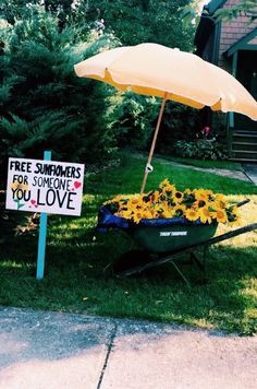 a wheelbarrow filled with sunflowers next to a sign that says free summers for someone you love