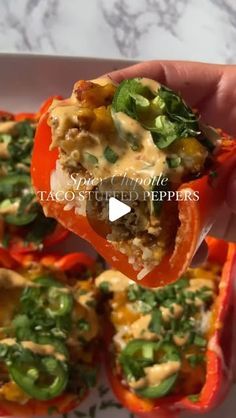 someone is holding up some stuffed peppers with cheese and vegetables in them on a white plate