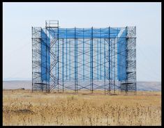 a large metal structure in the middle of a dry grass field with scaffolding on it