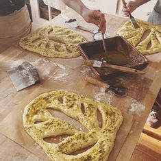 two people making homemade pizzas on a wooden table