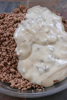 a glass bowl filled with meat and gravy next to a container of sauce