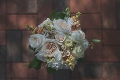 a bridal bouquet with white and pink flowers on a brick wall in the background