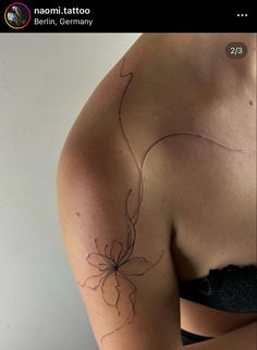 the back of a woman's shoulder with a flower tattoo on her left arm