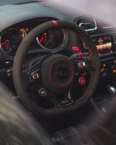 the interior of a car with red stitchs and steering wheel