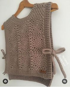 a crocheted sweater hanging on a wooden hanger