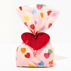 a heart - shaped balloon wrapped in cellophane and sitting on top of a pillow