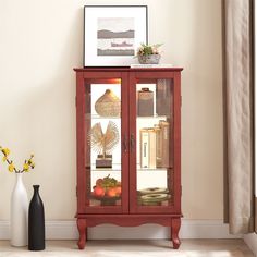 a red cabinet with glass doors sitting next to a vase