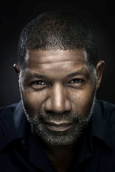 a close up of a person wearing a black shirt and beard with an intense look on his face