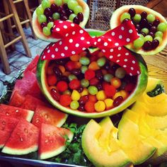 a mickey mouse bowl filled with candy and watermelon slices on top of a table