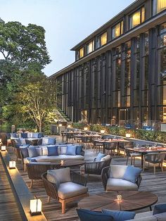 an outdoor dining area with tables and chairs on the wooden flooring, lit by candles