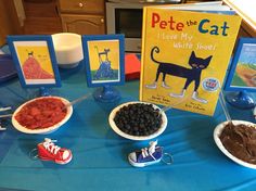 a table topped with plates and bowls filled with food next to a book about pete the cat