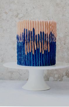 a blue and pink cake with icing on it sitting on top of a white plate