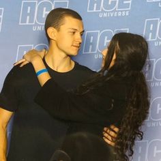 a man and woman embracing each other in front of a blue backdrop