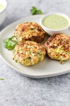 three crab cakes on a plate with dipping sauce