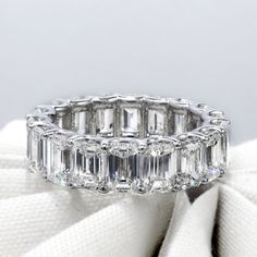 an emerald cut diamond ring on top of a white cloth