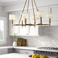 a kitchen with white cabinets and an island in front of the stove top is surrounded by fruit