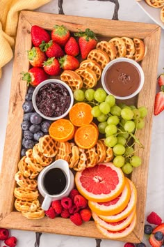 a wooden platter filled with fruit and waffles