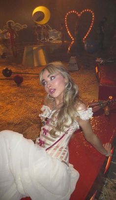 a woman sitting on top of a red bench wearing a white dress and headpiece