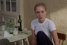 a woman sitting in front of a table with bottles on it