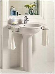 a white sink sitting under a bathroom mirror next to a wall mounted faucet