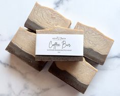 four soap bars sitting next to each other on a marble counter top with a business card