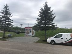 a white van is parked in front of a small kiosk and picnic table