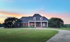 a large house sitting in the middle of a lush green field next to a road