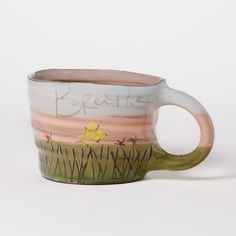 a ceramic mug with the words breathe painted on it's side and grass in the foreground