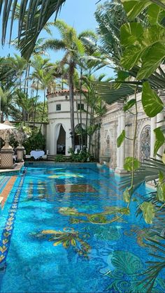 an outdoor pool surrounded by palm trees and blue tiles with fish swimming in the water