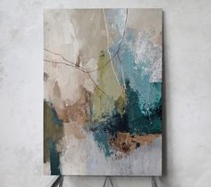 an abstract painting hangs on the wall above a white cabinet and blue chair in front of it