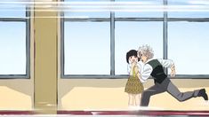 a man and woman are kissing in front of large windows, with one holding the other's head