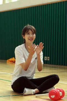 a woman sitting on the floor clapping with her hands