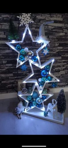 a christmas tree with lights and ornaments on it in front of a stone wall, surrounded by snowflakes