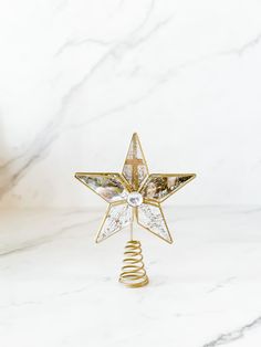 a gold christmas tree topper on a white marble surface with a spiral design in the shape of a star