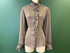 vintage 1970's taupe (cocoa brown) high neck, long-sleeve ruffled tuxedo blouse featuring a ribbon stripe throughout with puff shoulders and a ruffle down one side of bodice with a full button down front. please note:  photos give the blouse a grayish cast - true color is a light brown / taupe. ✂ measurements ✂ bust:  open to 38" waist:  open to 38" length:  26" label / maker:  Act III, size 14 condition:  very good.  no stains, tears or major flaws to note. Pinafore Skirt, Oc Board, Outfit References, Bridge City, Floral Playsuit, Seventies Fashion, Label Maker, Cocoa Brown, Wool Dress