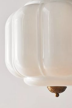 a white light hanging from the ceiling with a gold fixture on it's side