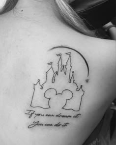 the back of a woman's shoulder with a disney castle tattoo