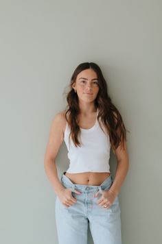 a woman standing in front of a wall with her hands on her hips