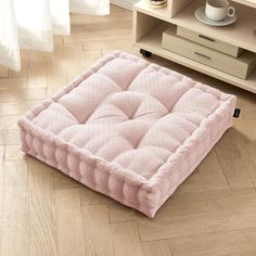 a pink mattress sitting on top of a wooden floor next to a coffee table and dresser