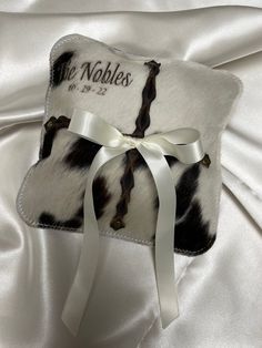 a cow print pillow with a white ribbon on it's side and the words, the nobles