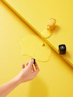 a hand holding a paint roller and painting the wall with an apple shape on it