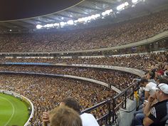 a large stadium filled with lots of people sitting on the bleachers and watching something