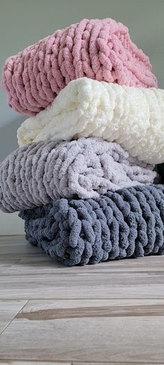 a pile of towels sitting on top of a wooden floor next to a black cat