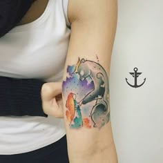 a woman's arm with a watercolor elephant tattoo on it and an anchor in the background