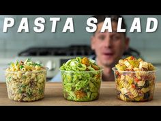 three plastic containers filled with pasta salad sitting on top of a table next to a man