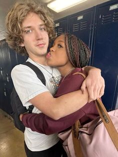 a man and woman hugging each other in front of lockers