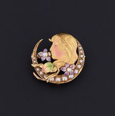 During the turn of the nineteenth century, artisans were inspired by the changing roles of women in society and began depicting the free flowing feminine form in brooches, bracelets, rings and more. This antique brooch (circa 1910) features a woman nestled in a pearl studded crescent adorned with enamel violets. The 14k gold brooch bears the makers mark for the renowned Krementz & Co. of Newark, NJ. The piece measures 0.7 inches from top to bottom by 0.8 inches wide, and it is in very good condi Art Deco Yellow Gold Collectible Brooches, Art Nouveau Yellow Gold Collectible Brooches, Collectible Cabochon Brooches, Yellow Gold Brooches For Anniversary, Art Nouveau Cabochon Brooches For Weddings, Collectible Art Nouveau Hallmarked Brooch, Art Nouveau Cabochon Wedding Brooches, Art Nouveau Yellow Gold Brooch Jewelry, Art Nouveau Brooch Jewelry As Gift