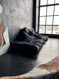 a dog laying on top of a couch in front of a window with a painting behind it