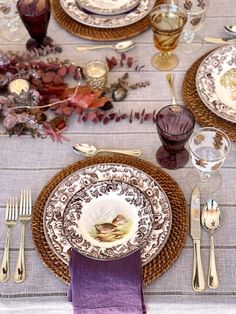 the table is set with plates, silverware and purple napkins for an elegant dinner