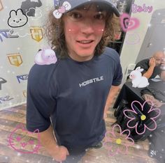 a man with curly hair wearing a blue shirt and hat standing in front of a mirror